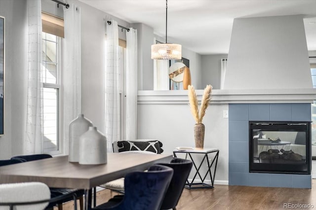 dining room with a tiled fireplace and wood finished floors