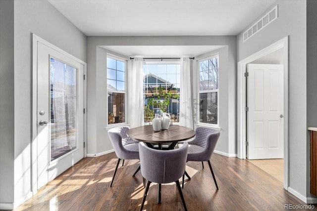 dining room featuring visible vents, baseboards, and wood finished floors