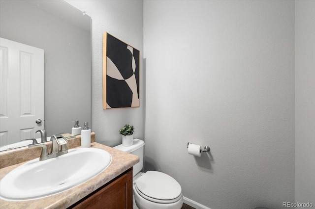 bathroom featuring a textured wall, vanity, and toilet