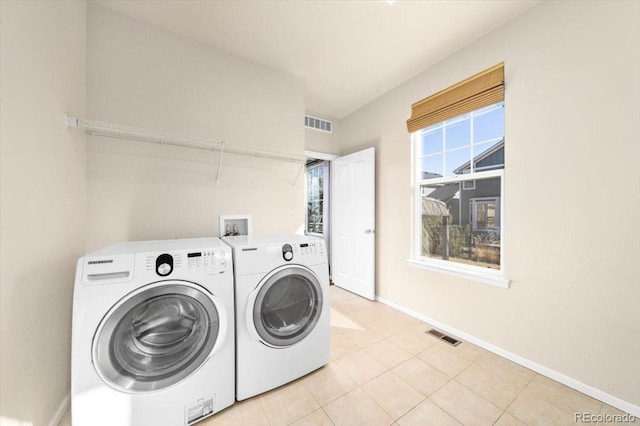 laundry room featuring light tile patterned floors, washing machine and dryer, laundry area, visible vents, and baseboards