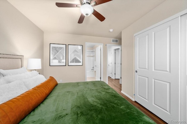 bedroom with visible vents, a ceiling fan, ensuite bath, wood finished floors, and baseboards