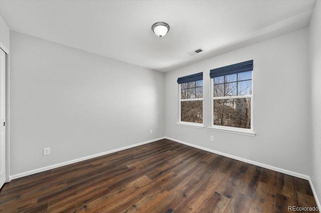 spare room with visible vents, dark wood finished floors, and baseboards