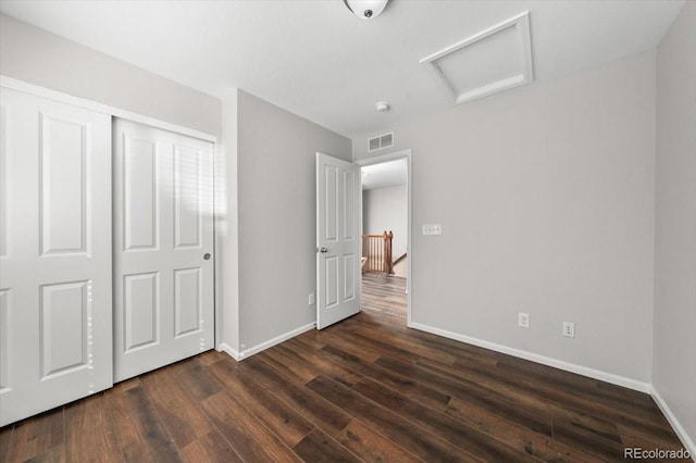 unfurnished bedroom featuring baseboards, dark wood finished floors, visible vents, and attic access