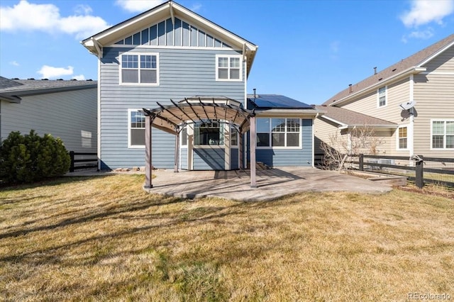 rear view of house featuring board and batten siding, a lawn, fence, a patio area, and a pergola