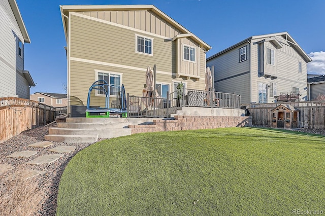 back of property featuring a trampoline and a lawn