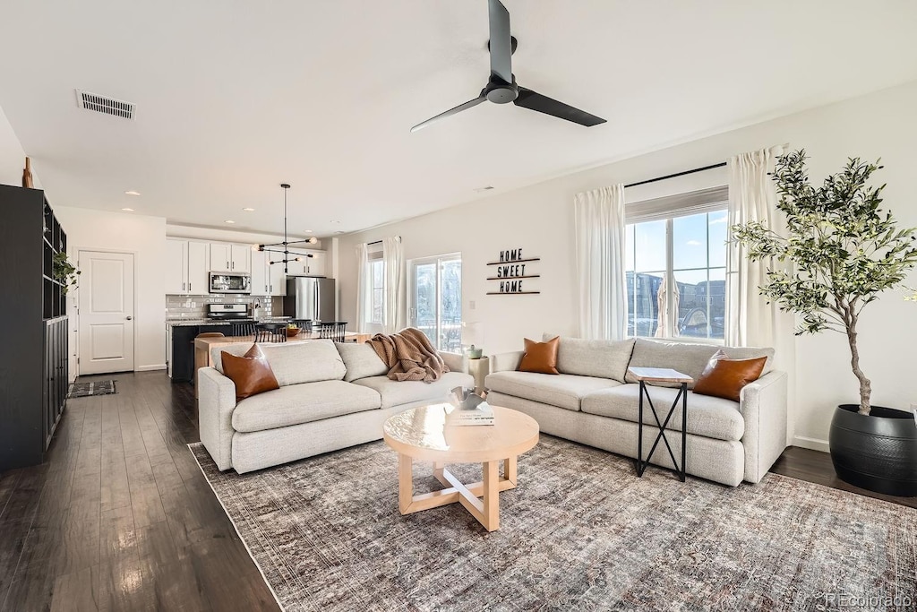 living room featuring ceiling fan, dark hardwood / wood-style floors, and a healthy amount of sunlight