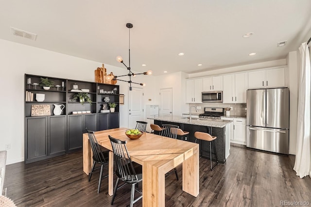 dining area featuring dark wood-type flooring, sink, and a notable chandelier