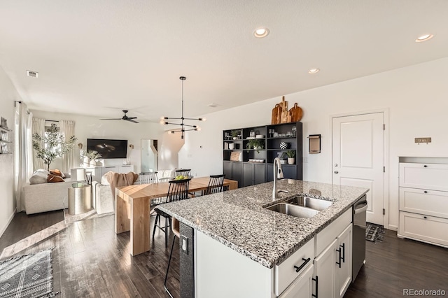 kitchen with sink, a kitchen island with sink, dark hardwood / wood-style floors, light stone countertops, and white cabinets