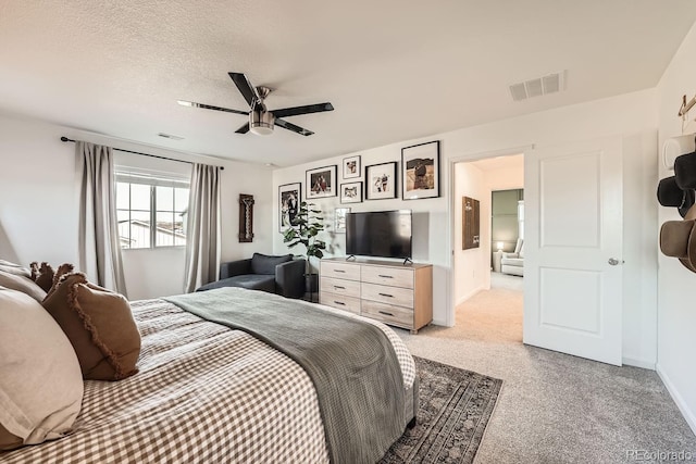 carpeted bedroom featuring ceiling fan and a textured ceiling