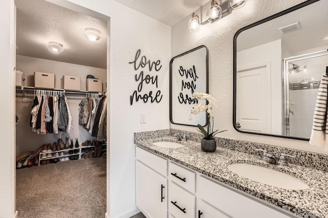 bathroom featuring vanity, a shower with shower door, and a textured ceiling