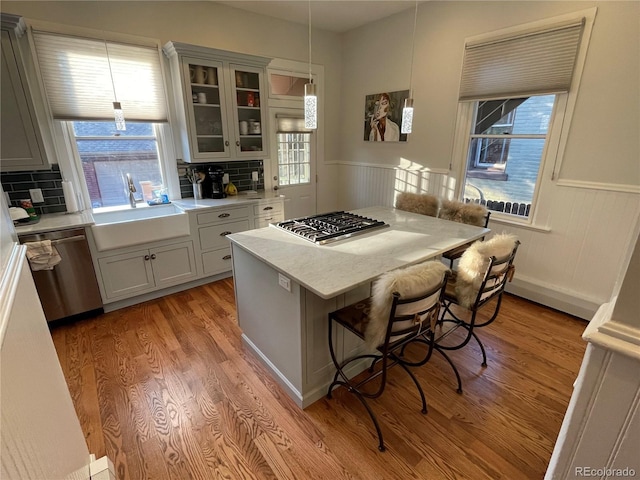 2335 Stout St, Denver, CO 80205 - kitchen with appliances with stainless steel finishes, a wainscoted wall, a sink, a kitchen island, and light countertops