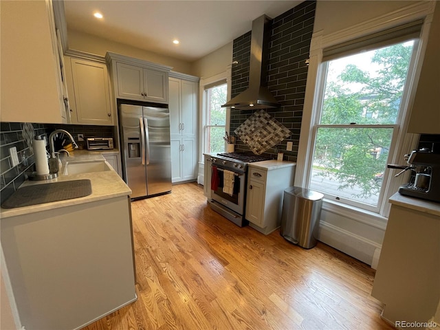 2335 Stout St, Denver, CO 80205 - kitchen featuring appliances with stainless steel finishes, wall chimney exhaust hood, a sink, light countertops, and healthy amount of natural light