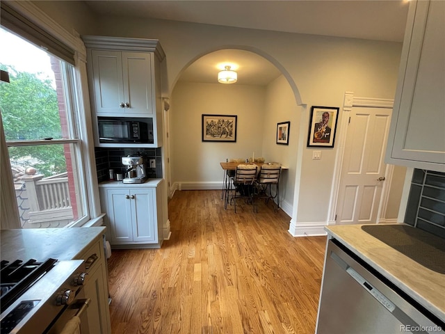 2335 Stout St, Denver, CO 80205 - kitchen featuring arched walkways, appliances with stainless steel finishes, light wood finished floors, and light countertops