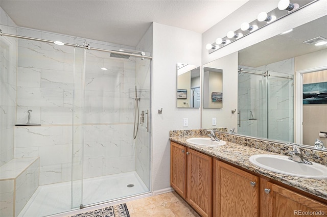 bathroom with vanity, a textured ceiling, an enclosed shower, and tile patterned flooring