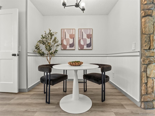 19726 Applewood Ct, Parker, CO 80138 - dining space featuring breakfast area, a textured ceiling, light wood-type flooring, wainscoting, and a chandelier