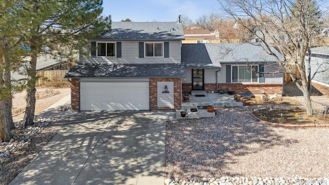 tri-level home with a garage, driveway, a shingled roof, and brick siding