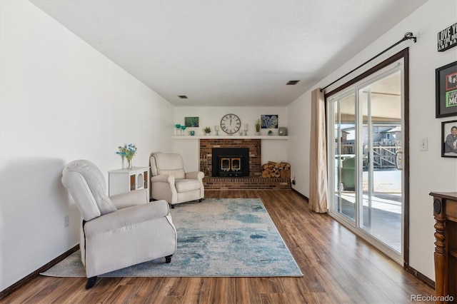 living room with baseboards, a fireplace, visible vents, and wood finished floors