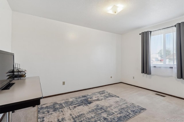 carpeted empty room featuring a textured ceiling, visible vents, and baseboards