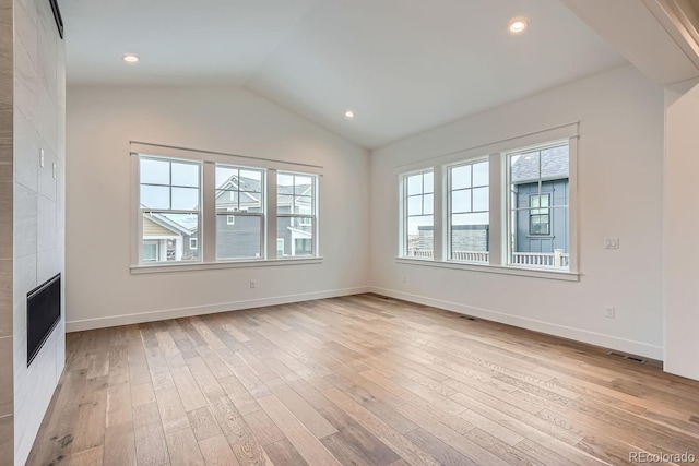 unfurnished living room with a fireplace, light wood-type flooring, and vaulted ceiling