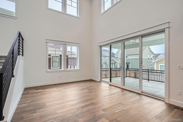 unfurnished living room featuring a high ceiling and hardwood / wood-style flooring