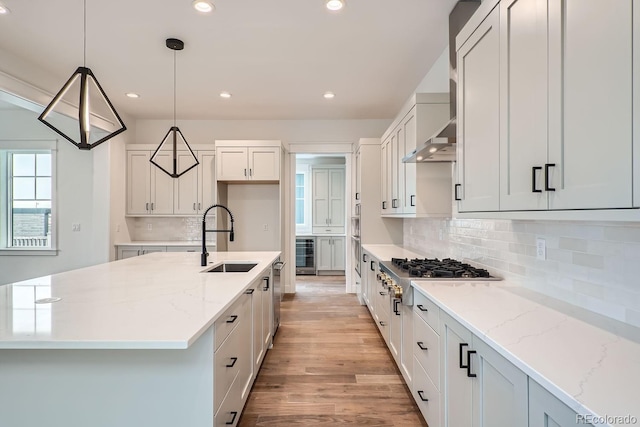 kitchen featuring sink, pendant lighting, white cabinetry, and a kitchen island with sink