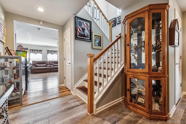 stairway with ceiling fan and hardwood / wood-style floors