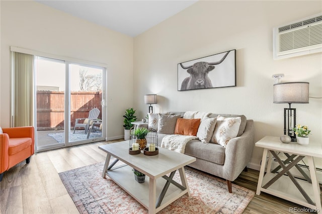 living area featuring an AC wall unit, baseboards, and wood finished floors