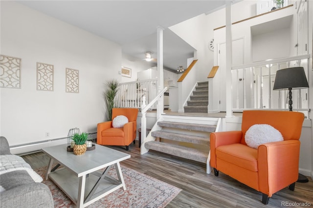 living room featuring stairway, wood finished floors, ceiling fan, and a baseboard radiator