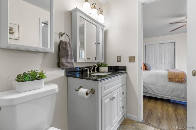 bathroom featuring toilet, connected bathroom, baseboards, ceiling fan, and vanity