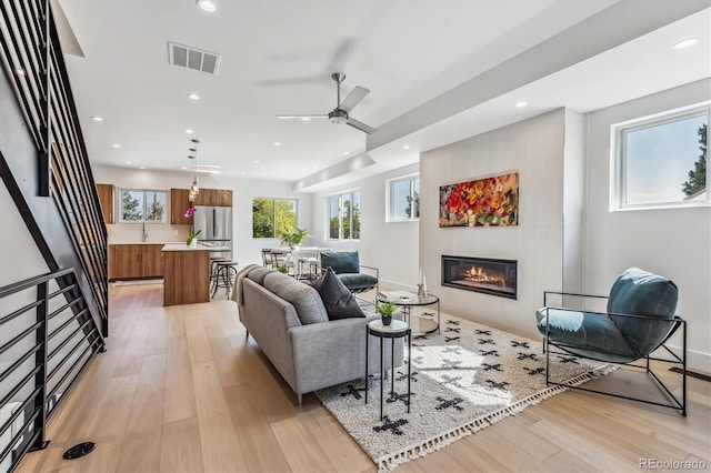 living room featuring ceiling fan and light hardwood / wood-style flooring