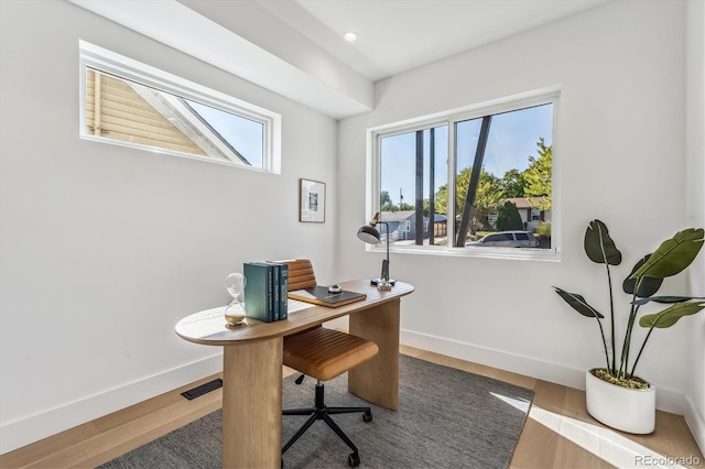 office with hardwood / wood-style floors and a healthy amount of sunlight