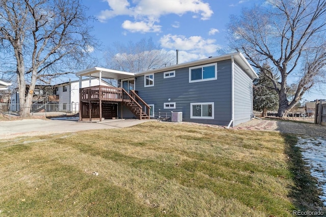 rear view of property featuring a yard, central AC unit, and a wooden deck