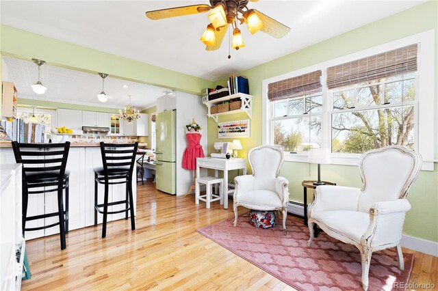 7835 Valley View St, Louviers, CO 80131 - sitting room featuring light wood-type flooring, a ceiling fan, a baseboard radiator, and a chandelier