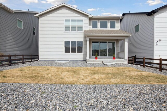 rear view of house with a yard and fence