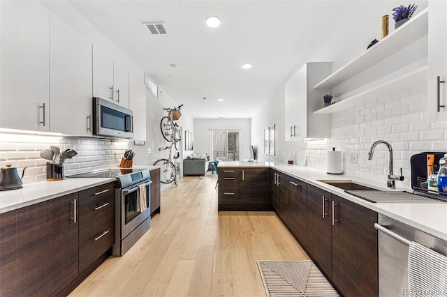 kitchen with stainless steel appliances, light wood-type flooring, decorative backsplash, and white cabinets