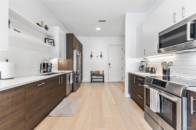 kitchen with appliances with stainless steel finishes, tasteful backsplash, white cabinetry, sink, and dark brown cabinetry