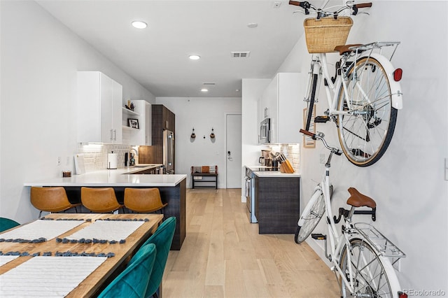 kitchen featuring white cabinetry, appliances with stainless steel finishes, kitchen peninsula, and backsplash