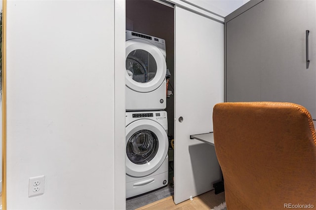 laundry room featuring stacked washer and clothes dryer and light hardwood / wood-style flooring