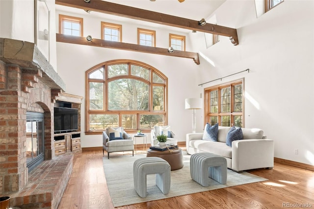 living room featuring baseboards, a fireplace, a high ceiling, and wood finished floors