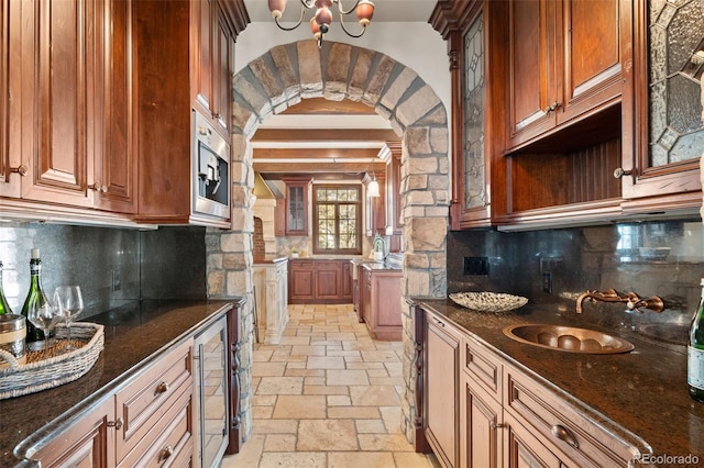 kitchen featuring a sink, stone tile floors, wine cooler, and dark stone countertops