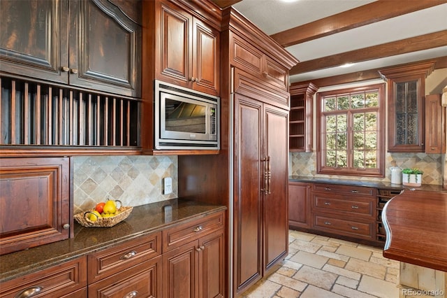 kitchen with stone tile floors, decorative backsplash, built in study area, and built in appliances