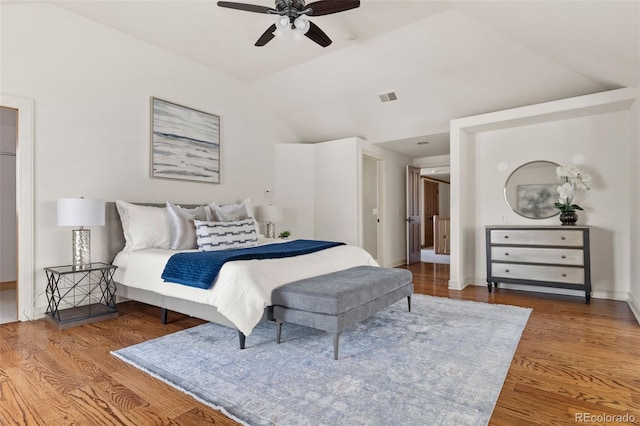 bedroom with lofted ceiling, visible vents, baseboards, and wood finished floors