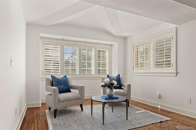 living area with lofted ceiling, wood finished floors, and baseboards