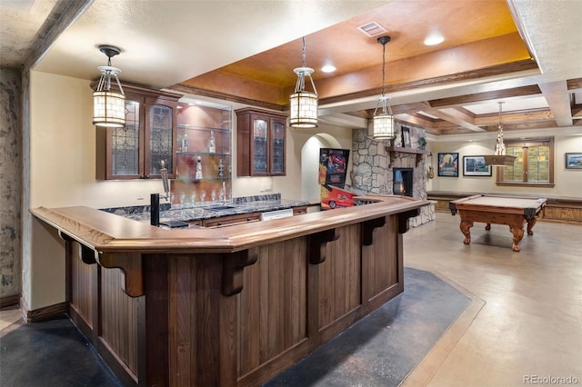 bar featuring indoor wet bar, finished concrete flooring, visible vents, hanging light fixtures, and a stone fireplace