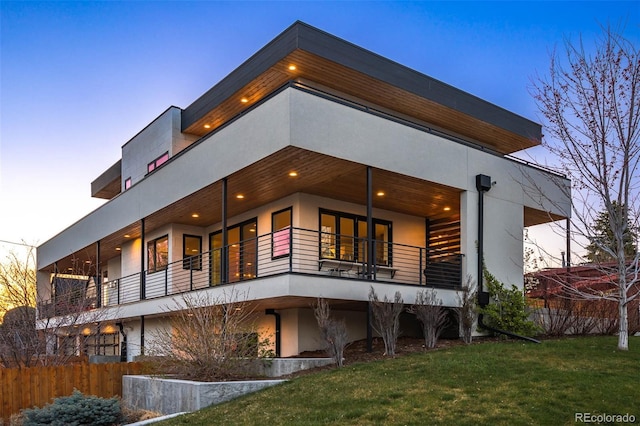 back of property featuring a yard, stucco siding, and fence