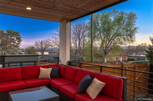 patio terrace at dusk featuring an outdoor hangout area, a balcony, and fence
