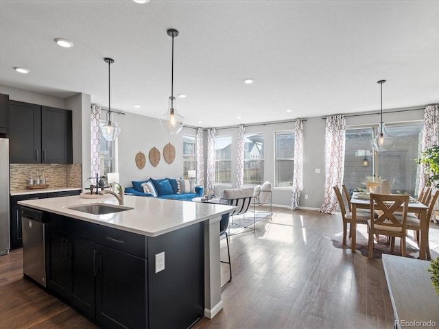 kitchen with sink, wood-type flooring, stainless steel appliances, and a center island with sink