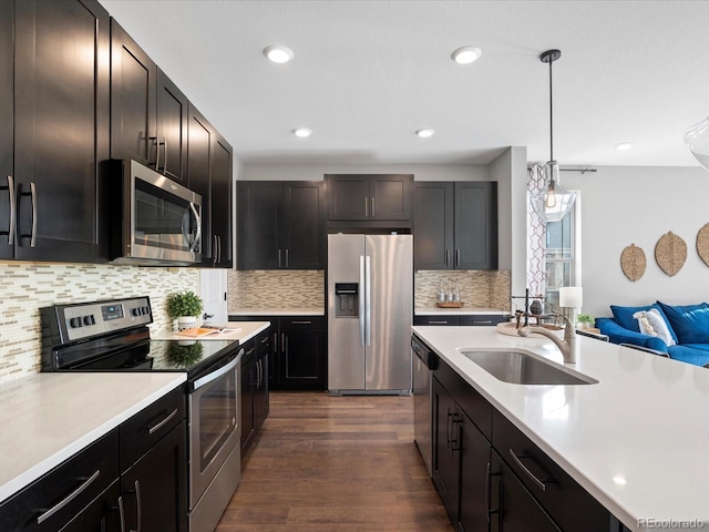 kitchen with dark wood-type flooring, sink, hanging light fixtures, stainless steel appliances, and decorative backsplash