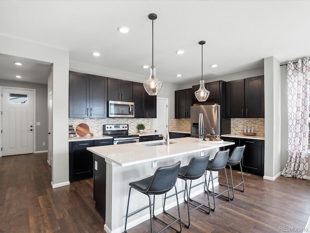 kitchen featuring decorative light fixtures, sink, a kitchen breakfast bar, stainless steel appliances, and a center island with sink