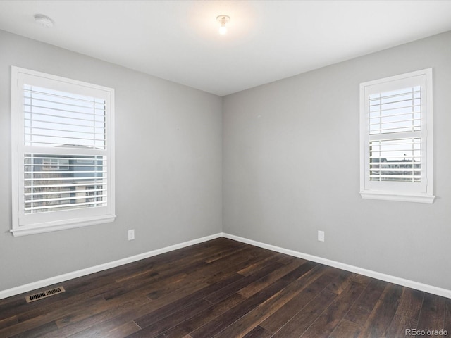 spare room with dark wood-type flooring and a wealth of natural light